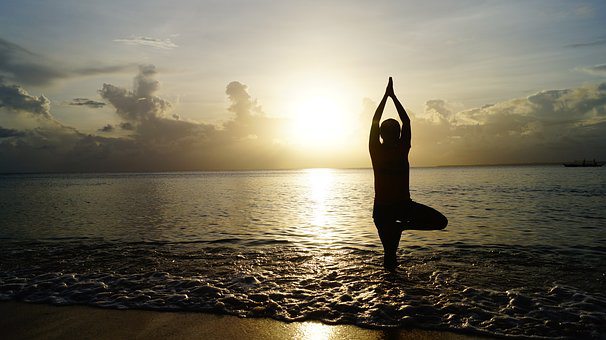 senior doing tree pose at beach