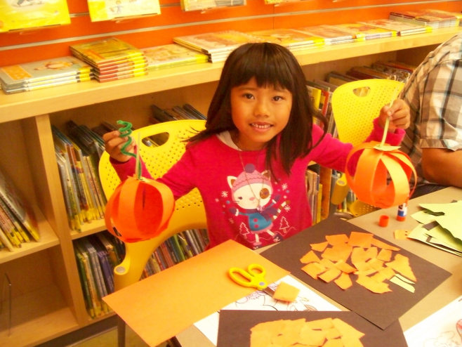 little girl with paper pumpkins